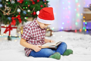 Sevimli küçük çocuk okuma kitabı Noel ağacı arka plan üzerinde