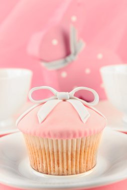 Çay seti ve süslemeleri üzerinde pembe bir arka plan ile lezzetli kek