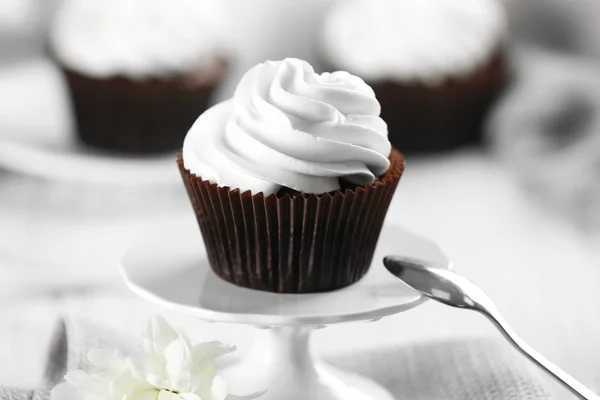 Delicious chocolate cupcake with cream on served table, close up — Stock Photo, Image