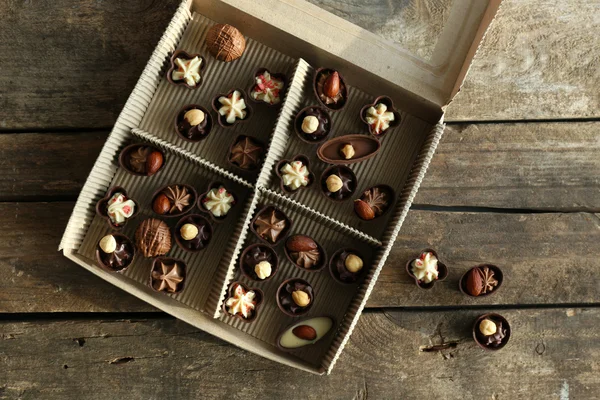 Διαφορετικές καραμέλες από σοκολάτα σε χάρτινο κουτί σε ξύλινα φόντο, κοντινό πλάνο — Φωτογραφία Αρχείου