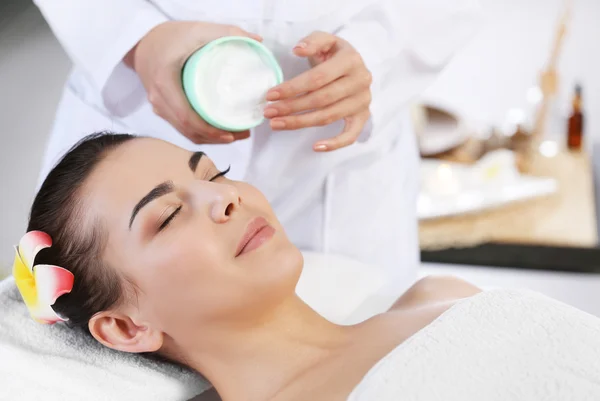 Massaggiatore mettendo crema sul viso della donna — Foto Stock