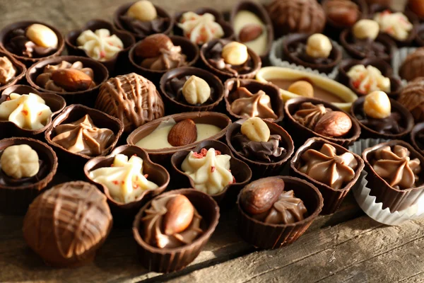 Deliciosos caramelos de chocolate sobre fondo de madera, de cerca —  Fotos de Stock