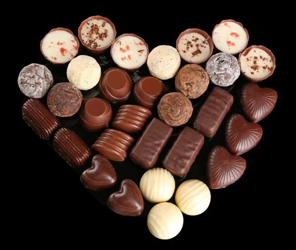 Bonbons au chocolat assortis en forme de coeur sur fond noir — Photo