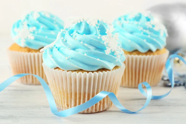 Wenige leckere blaue Cupcakes mit Dekorationen auf hellem Hintergrund — Stockfoto