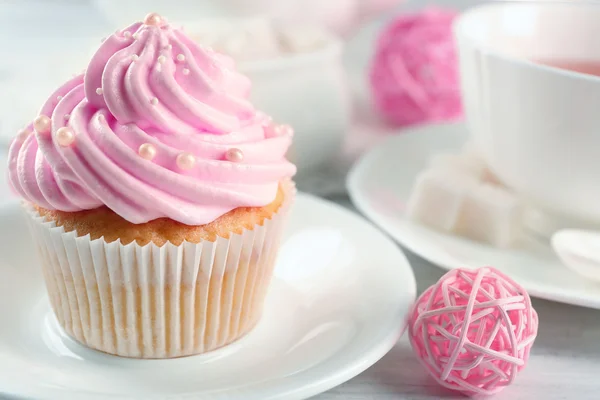 Tasty pink cupcake with cup of tea and decorations, closeup — Stock Photo, Image