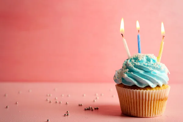 Leckere Cupcake mit Kerze auf rosa Hintergrund dekoriert — Stockfoto