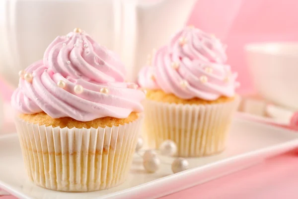 Dois saborosos cupcakes rosa e bule de chá, close-up — Fotografia de Stock