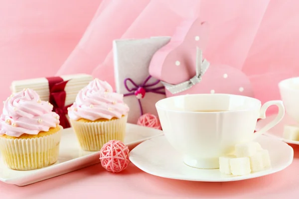 Leckere Cupcakes mit Geschenken und Dekorationen auf rosa Hintergrund — Stockfoto