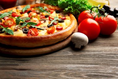 Ahşap masa üzerinde sebze ile lezzetli pizza