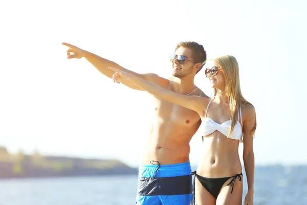 Pareja feliz apuntando a la playa — Foto de Stock