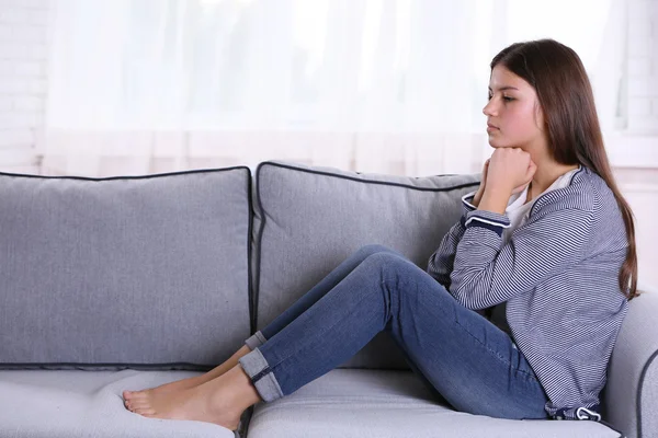 Verärgertes Mädchen sitzt auf dem Sofa — Stockfoto