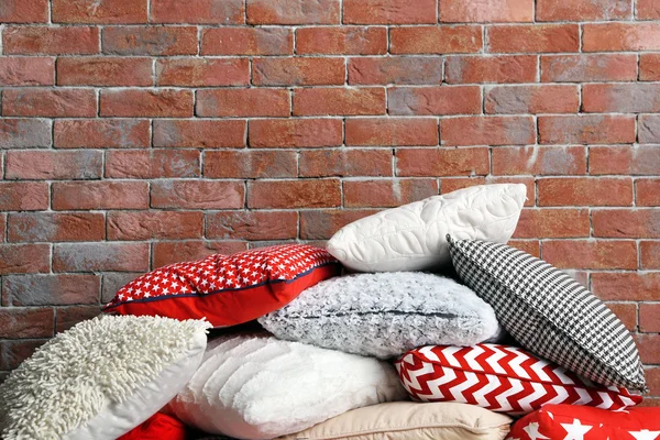Multicolour pillows on brick wall — Stock Photo, Image