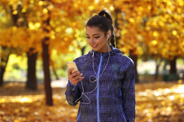 Mujer sosteniendo el teléfono en otoño parque —  Fotos de Stock