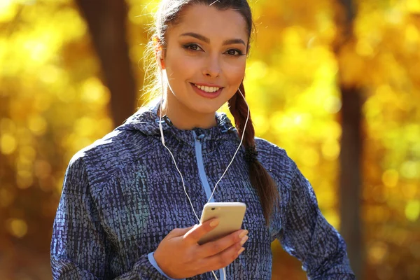 woman holding phone in autumn park
