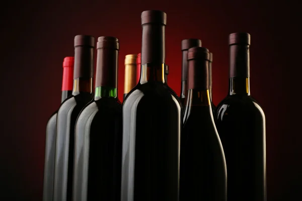 Koyu kırmızı zemin üzerine üst üste şişe şarap, yakın çekim — Stok fotoğraf