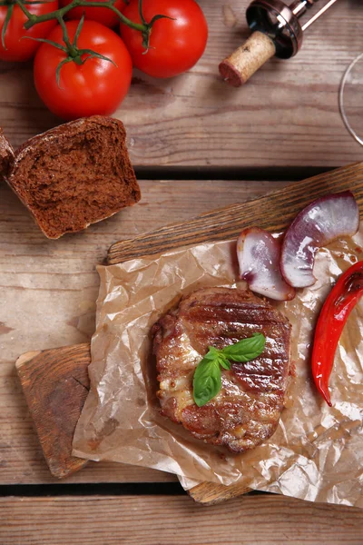 Filé de carne assada e legumes na tábua de corte, sobre fundo de madeira — Fotografia de Stock