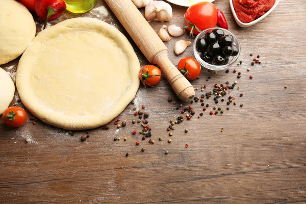 Teigbasis und Zutaten für Pizza, auf dem Tisch — Stockfoto