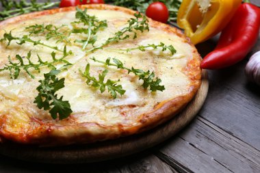 Lezzetli pizza ahşap arka plan üzerinde sebze ve otlar ile dekore edilmiş, yakın çekim