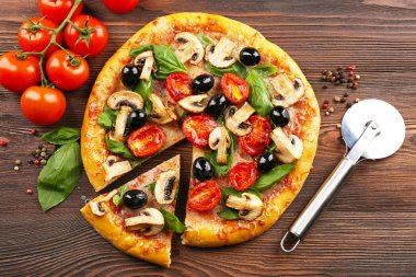 Sebze ile lezzetli lezzetli pizza ahşap masanın üzerine dilimlenmiş