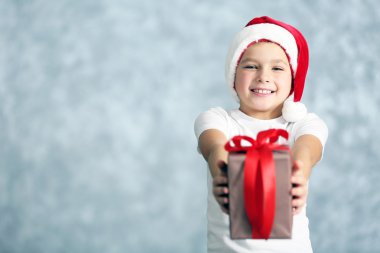 Hediye kutusu ile Noel Baba şapkalı çocuk 