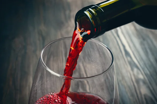 Pouring red wine on wooden background — Stock Photo, Image