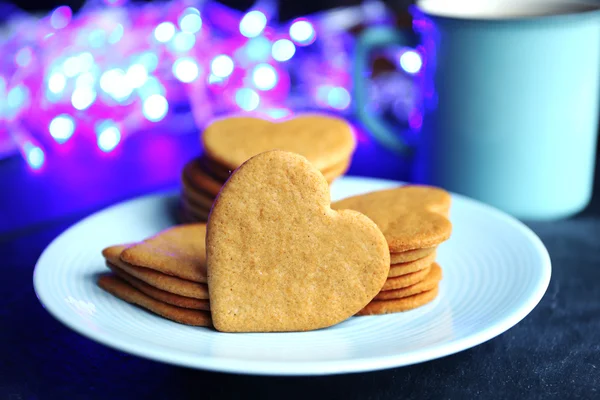 Biscotti a forma di cuore su piatto e tazza su un tavolo — Foto Stock