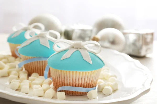 Cupcakes saborosos com arco e brinquedos de Natal na cor de fundo de madeira — Fotografia de Stock