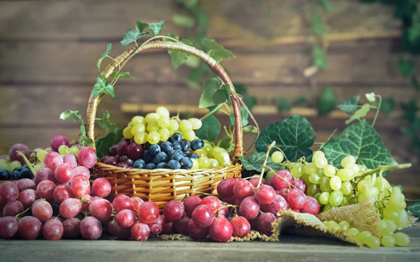 Grape in basket on wooden table — Stock Photo, Image