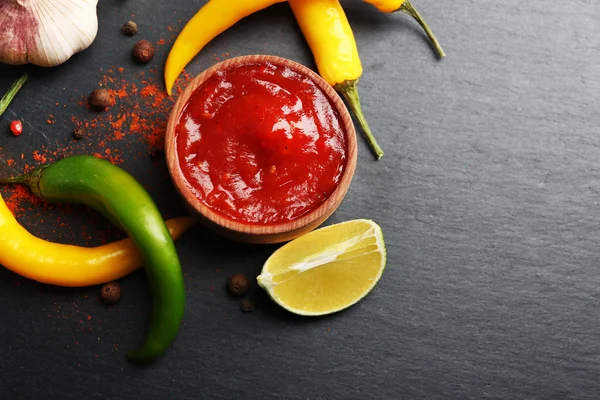 Salsa picante casera y especias sobre fondo oscuro — Foto de Stock