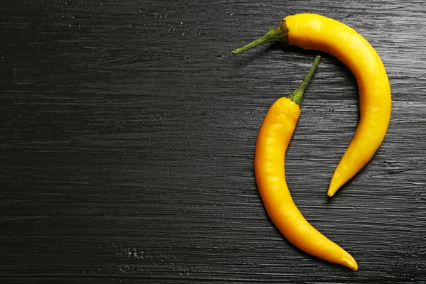 Žlutá chili peppers na tmavém pozadí dřevěná — Stock fotografie