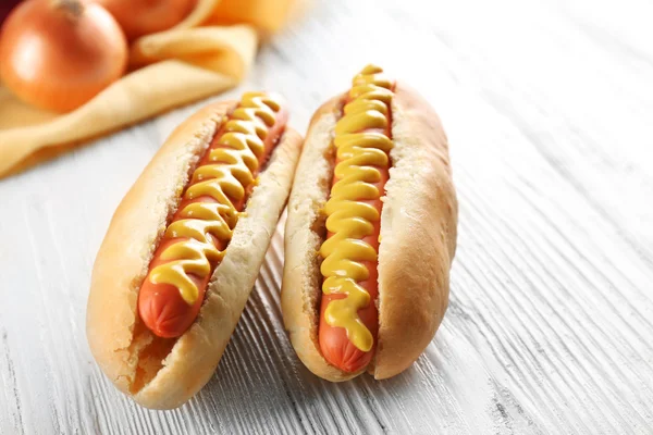 Perros calientes y cebollas frescas sobre fondo de madera — Foto de Stock