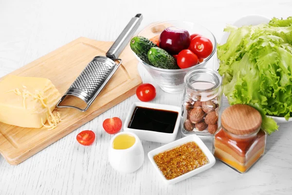 Ustensiles de cuisine et ingrédients pour salade sur table, sur fond clair — Photo