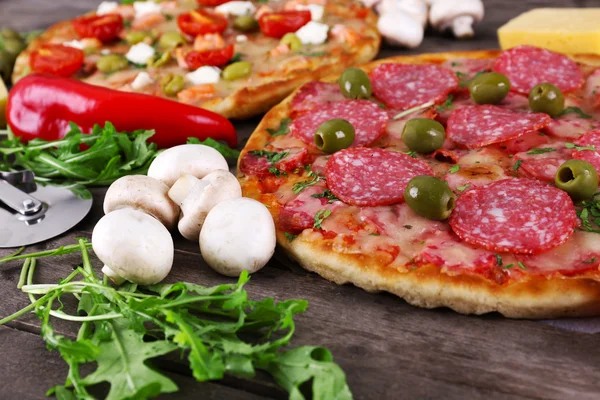 Deliziosa e gustosa pizza con ingredienti in tavola, primo piano — Foto Stock