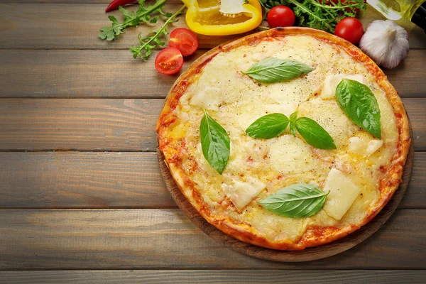 Pizza savoureuse décorée avec du basilic et des légumes sur fond bois, gros plan — Photo