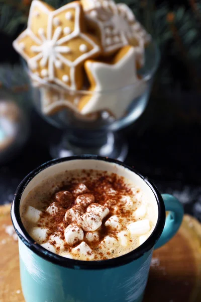 Mugg av heta cacao med marshmallow och cookies på svart bord — Stockfoto