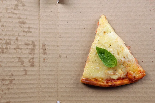 Leckere Pizzascheiben mit Basilikum auf Karton, Nahaufnahme — Stockfoto