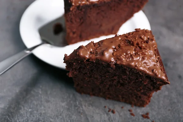 Délicieuse tranche de gâteau au chocolat avec crème aux noix sur plaque blanche sur fond gris, gros plan — Photo