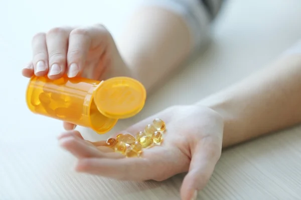 Vrouw morsen gele medische capsules — Stockfoto