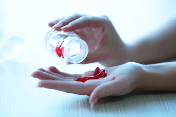 Femme renverse des capsules médicales rouges — Photo