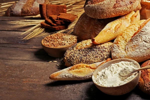 Vers gebakken brood, meel en tarwe op de houten tafel — Stockfoto