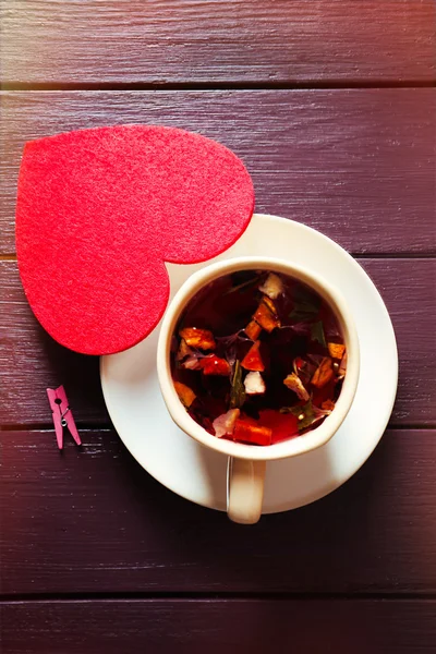 Xícara de chá de frutas em um limpet com coração vermelho no fundo de madeira closeup — Fotografia de Stock