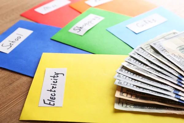 Envelopes coloridos com dinheiro para necessidades em fundo de madeira — Fotografia de Stock