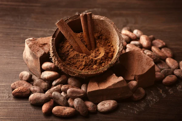 Kom met aromatische cacaopoeder en groene blad op houten achtergrond, close-up — Stockfoto