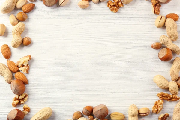 Ram med blandning av nötter i tabellen vit trä — Stockfoto