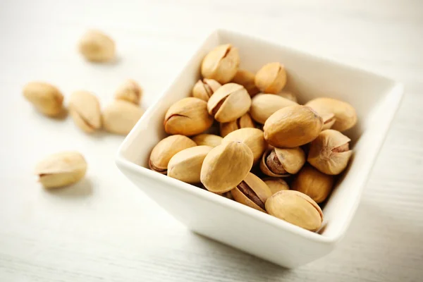 Pistachos en el bowl sobre fondo blanco de madera — Foto de Stock