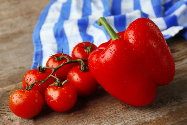 Piros paprika, paradicsom a fa háttér csíkos pamut szalvéta közelről — Stock Fotó