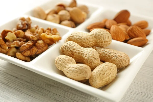 Valnöt-kärnor, mandel, pistagenötter, jordnötter i keramiska rektangel plattan, närbild — Stockfoto