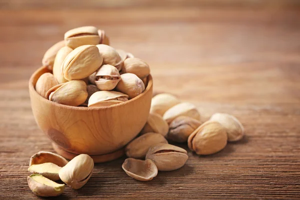 Pistachios in the wooden bowl on the table, close-up — Stock Photo, Image