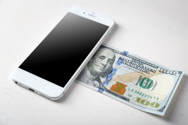 Smart phone and dollar banknote on light table. Telephone charges — Stock Photo, Image