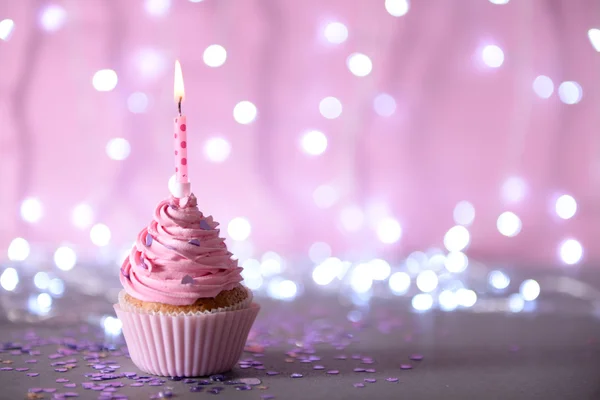 Cupcake med rosa grädde glasyr och ljus — Stockfoto